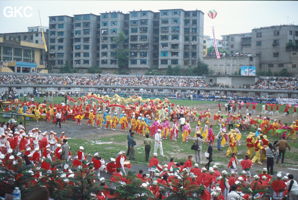 Grande fête pour célébrer le retour de Hong Kong à la Chine. Une foule à faire pâlir les commissions de sécurité les plus laxistes, les couleurs vives des costumes d'une multitude de figurants contrastent avec la grisaille des bâtiments alentours. Et le tout pour un spectacle de deux heures ou se côtoient le pire et le meilleur... Stade de Liupanshui (Suicheng, Guizhou)